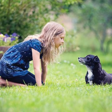 Young girl plays with dog outside
