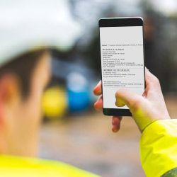 Person in high-vis gear holding phone.