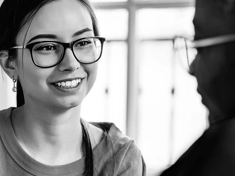 Smiling woman with glasses talking to man.