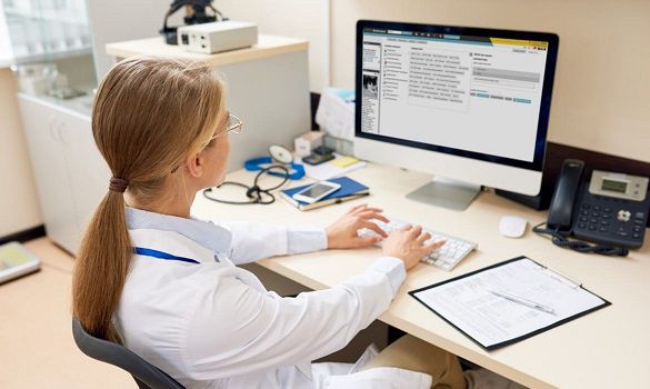 Veterinarian with a blond ponytail using IDEXX Animana on a desktop